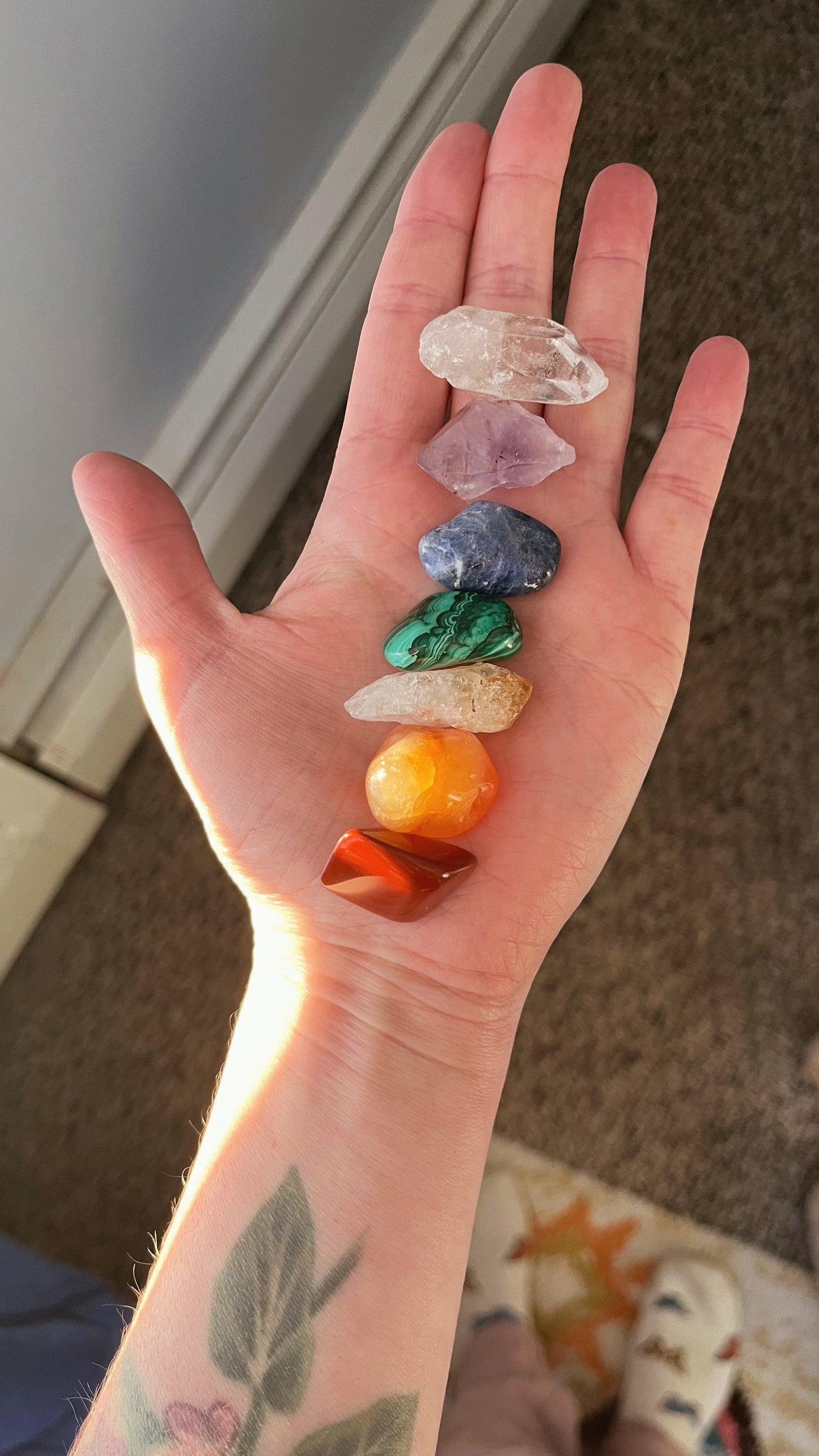 Hand holding a collection of colorful crystals with a neutral background